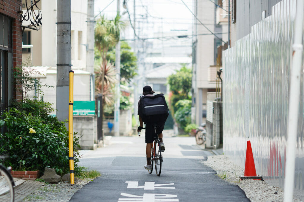 狭い道を自転車で通っている配達員