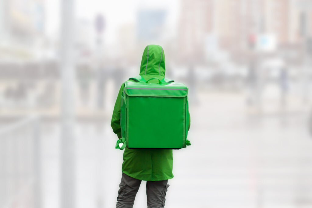 緑の雨具を着た配達員