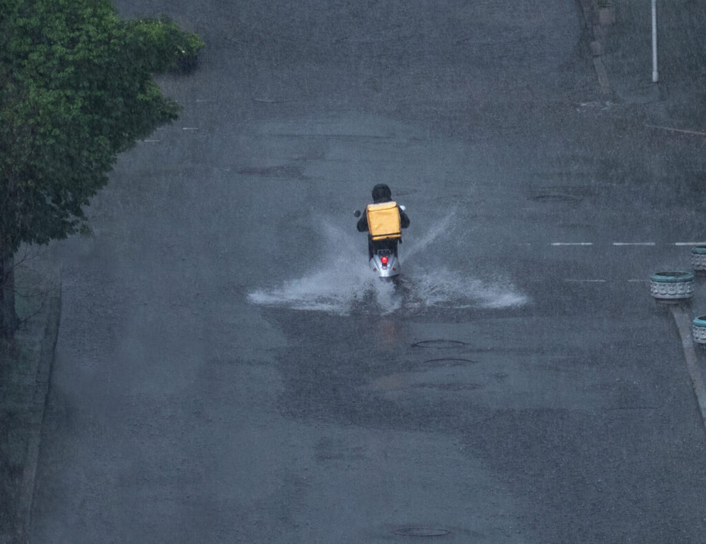 大雨のなかで配達する配達員