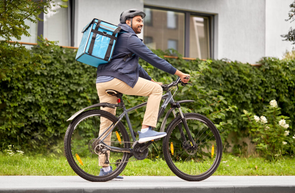 水色の配達バックを持った自転車に乗る男性