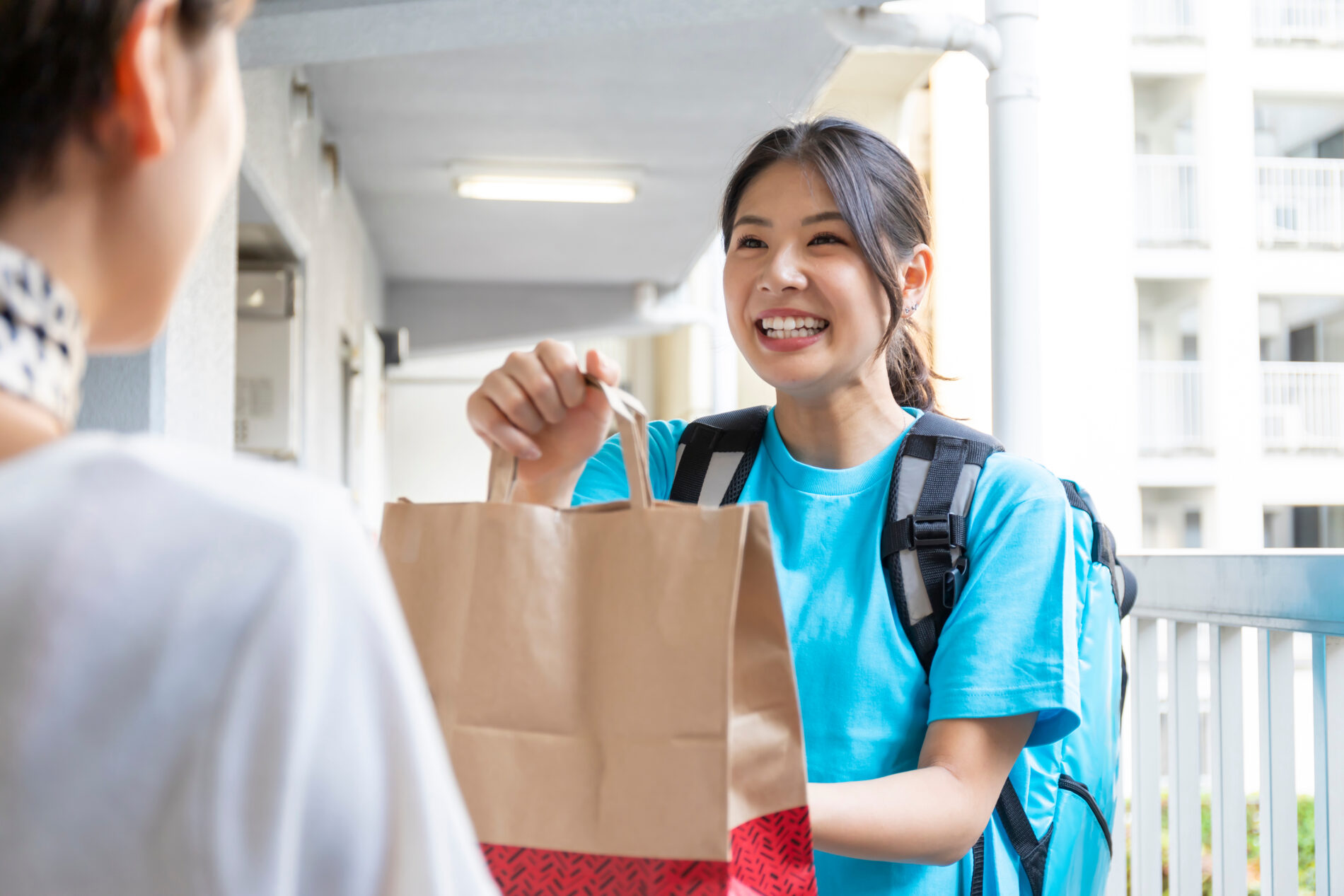 笑顔で紙袋を渡す女性