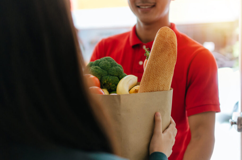 笑顔で紙袋に入った食材を手渡す男性