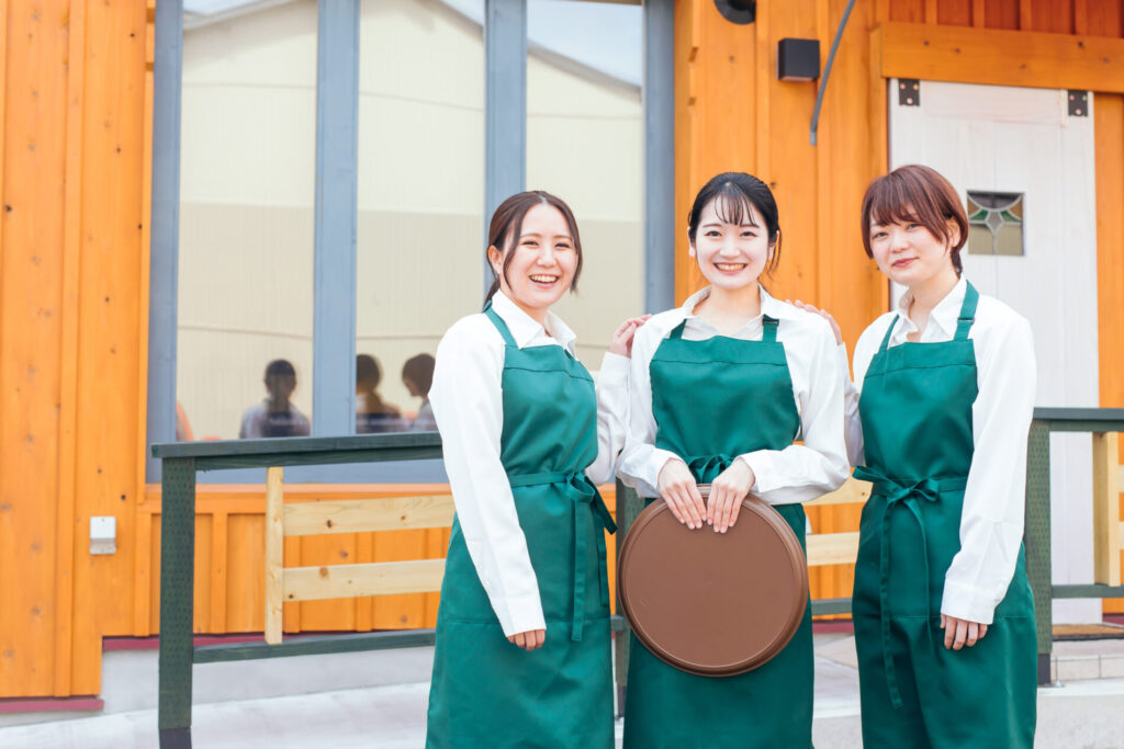 緑のエプロンを着た3人の女性スタッフ